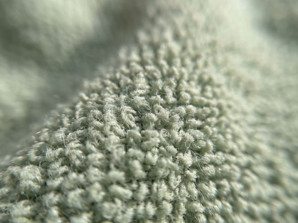 Extreme close-up of the looped weave of a pale sage microfibre cloth.