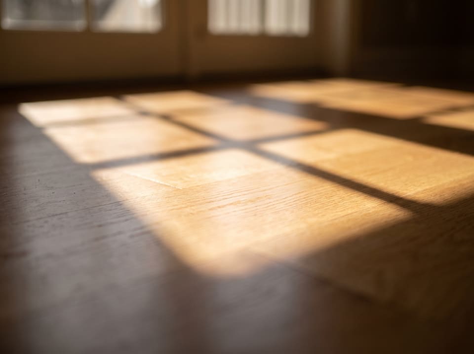 Morning window light falling in soft panes across a pale oak floor.